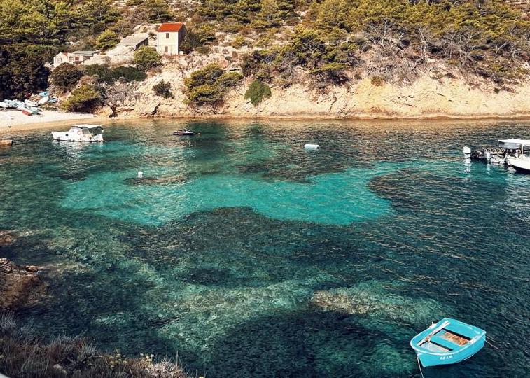 A picturesque view of the rugged coast and the tranquil waters of the Croatian Coast along with a few boats sailing peacefully. 