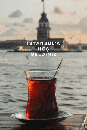  A glass of traditional Turkish tea served on a saucer, placed against the backdrop of Istanbul's iconic Maiden's Tower at sunset, with seagulls flying above. The text "İstanbul'a Hoş Geldiniz" (Welcome to Istanbul) is overlaid on the image.