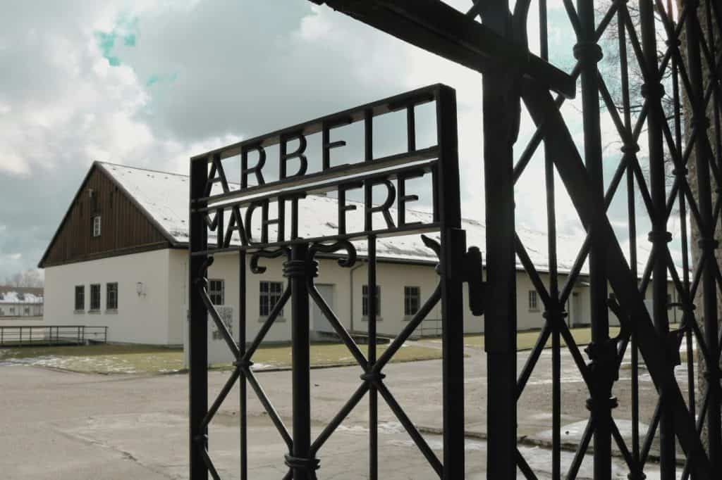 The entrance gate of Dachau Concentration Camp in Germany, with the infamous inscription "Arbeit Macht Frei" (Work Sets You Free), standing as a chilling reminder of history. As one of the most significant historical sites near Munich, visiting Dachau is an essential experience for those reflecting on the past and learning about WWII, making it a sobering yet important part of "Things to do in Munich."