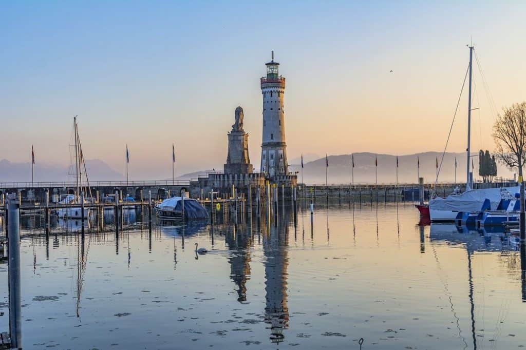 "A tranquil sunrise over Lake Constance with a lighthouse reflected in the calm waters—a peaceful retreat for couples looking for waterfront honeymoon destinations in Germany