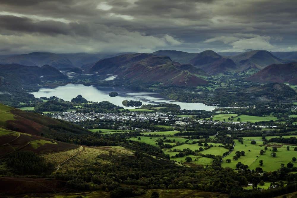  A stunning aerial view of green valleys, a glistening lake, and surrounding mist-covered mountains—ideal for those seeking picturesque honeymoon destinations in forest regions.