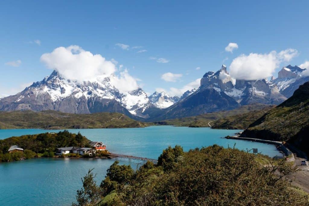 Snow-capped peaks rise above turquoise waters, with a cozy lodge nestled in the forested terrain—an adventurous escape for couples seeking honeymoon destinations in forest and mountain landscapes.