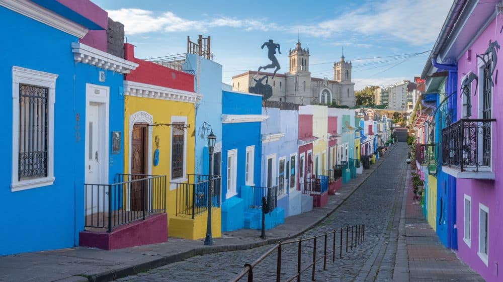 A image of the La Boca district. The colorful street with vibrant houses. The sun is shining and the sky is blue making it the best honeymoon destination in February