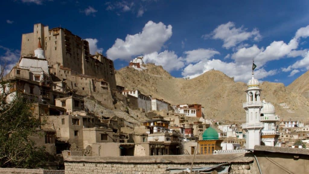 Ancient Leh Palace and surrounding heritage structures, with a white mosque in the foreground and Namgyal Tsemo Monastery perched atop the hill—capturing the cultural blend of a leh ladakh itinerary.