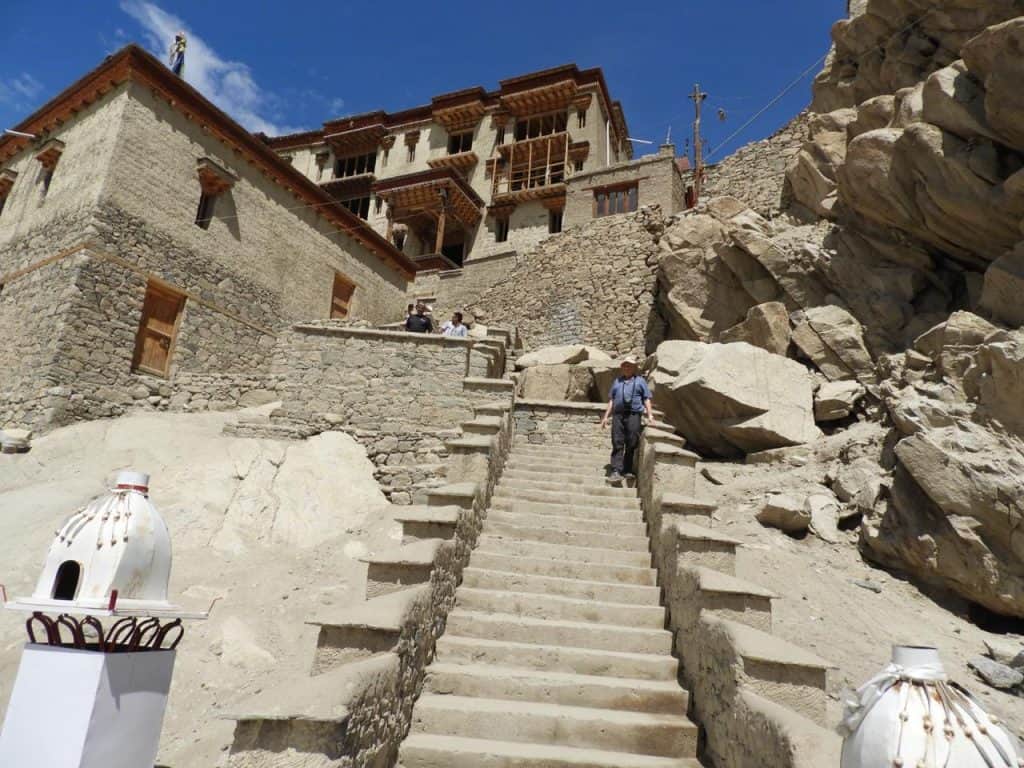 View of Shey Palace with its tiered stone structure and golden chorten in the backdrop of barren hills under a bright blue sky, an iconic stop in a leh ladakh itinerary.